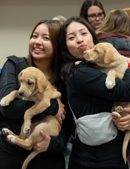 Two students holding puppies