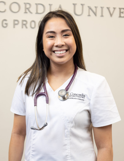 Nursing student standing in front of a tan wall with a Concordia logo on it